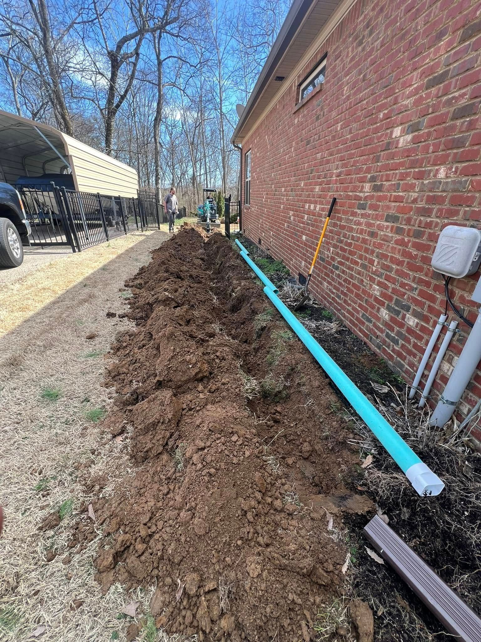A drain pipe is being installed on the side of a brick building.