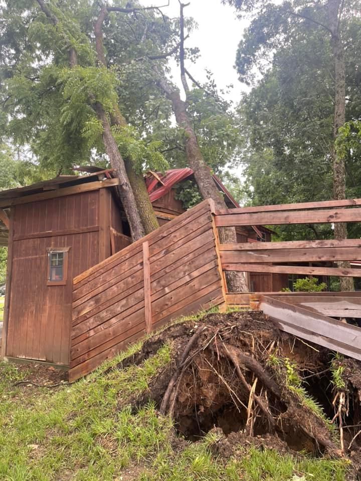A wooden fence is leaning against a shed in the woods.