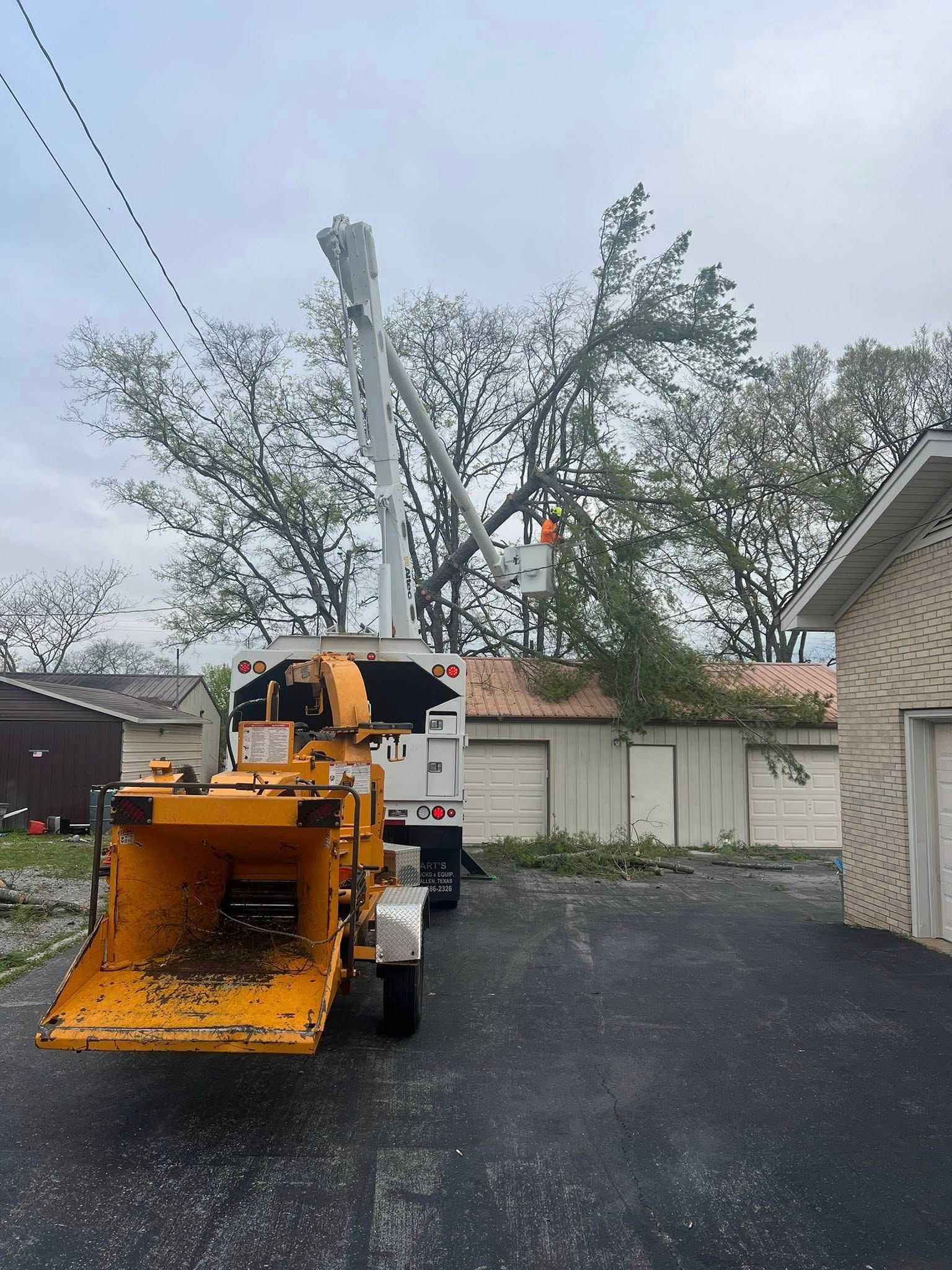 A tree chipper is parked in front of a garage.