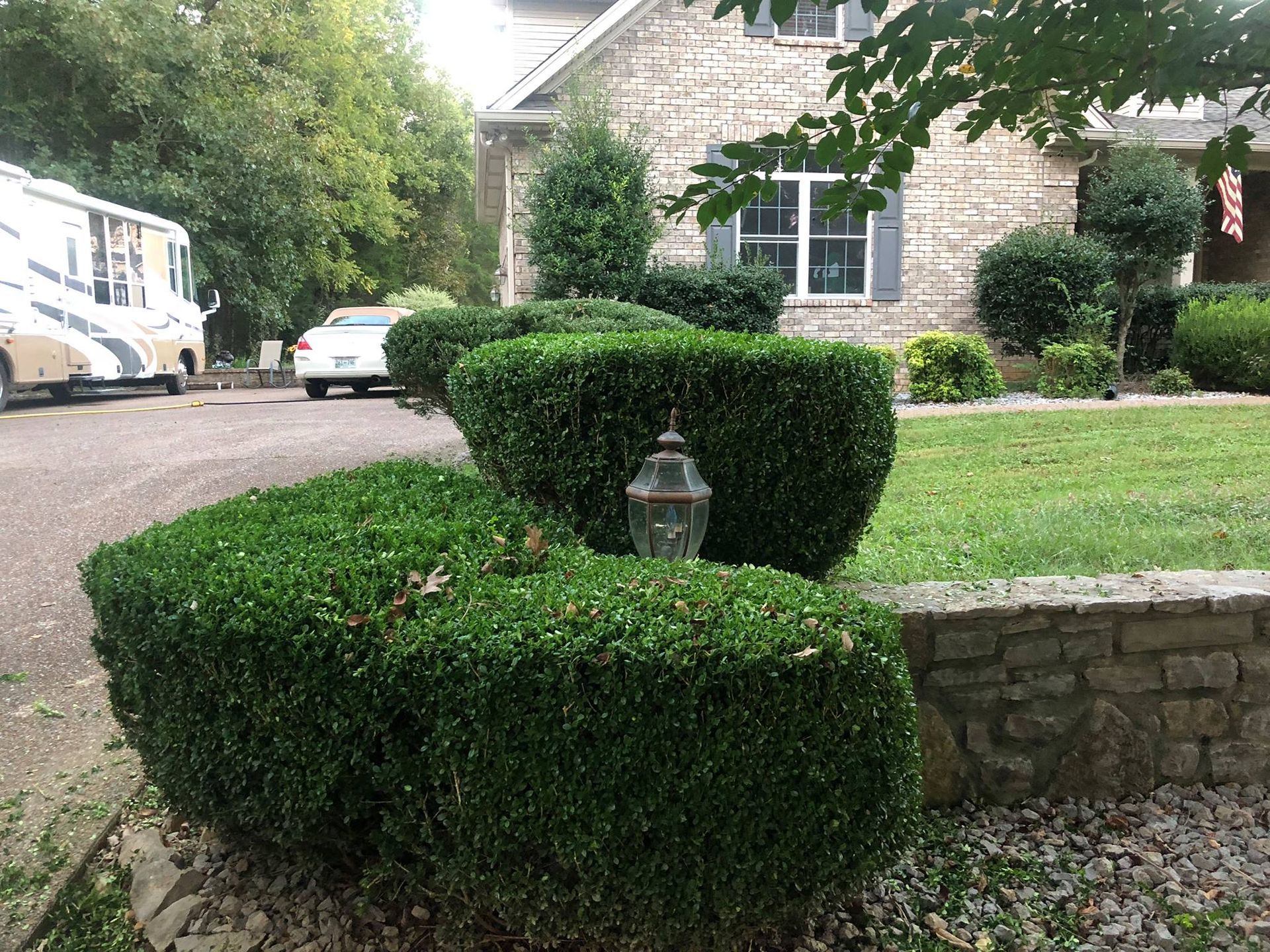 A house with a rv parked in front of it and bushes in front of it.