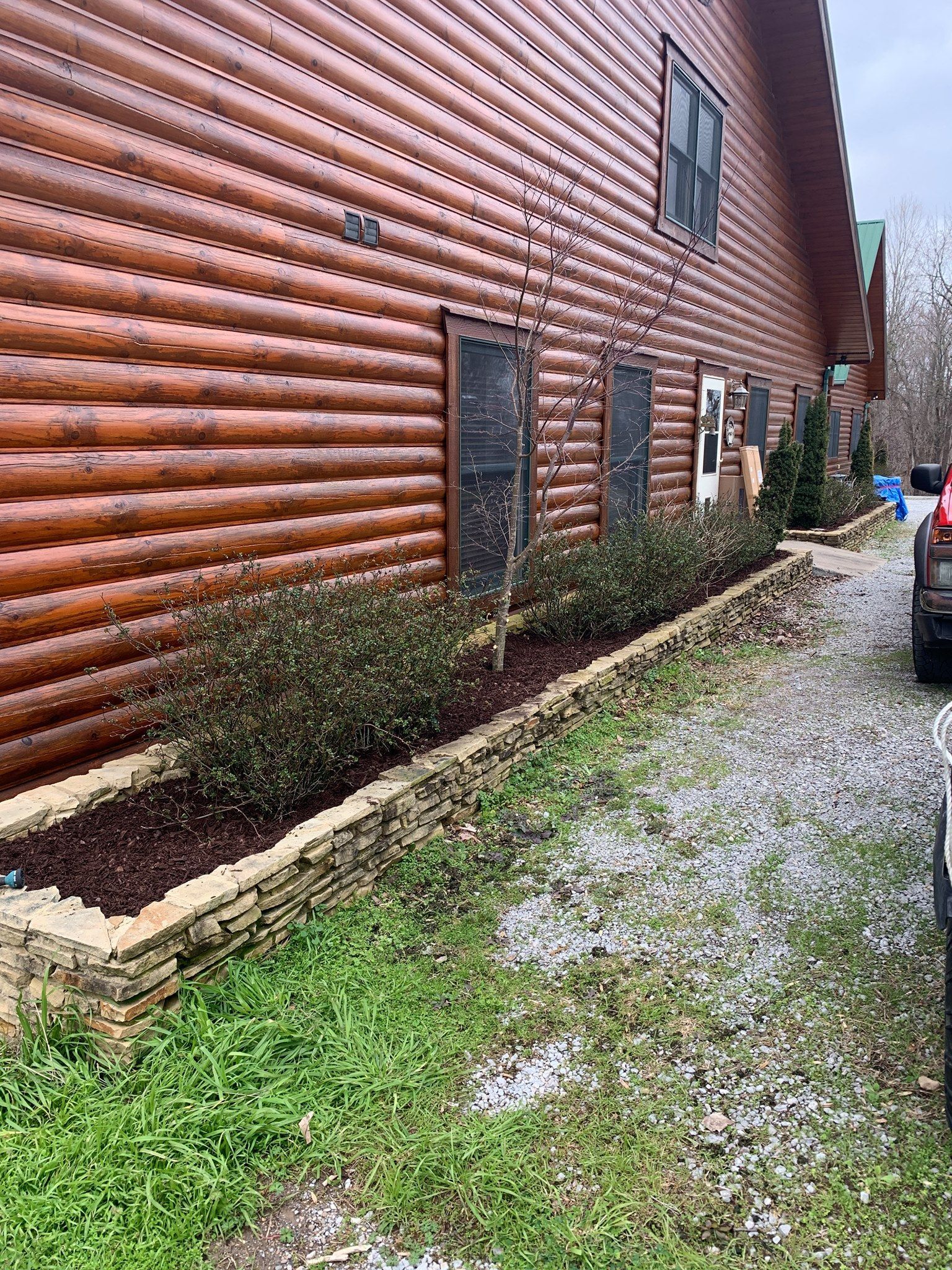 A car is parked in front of a log cabin.