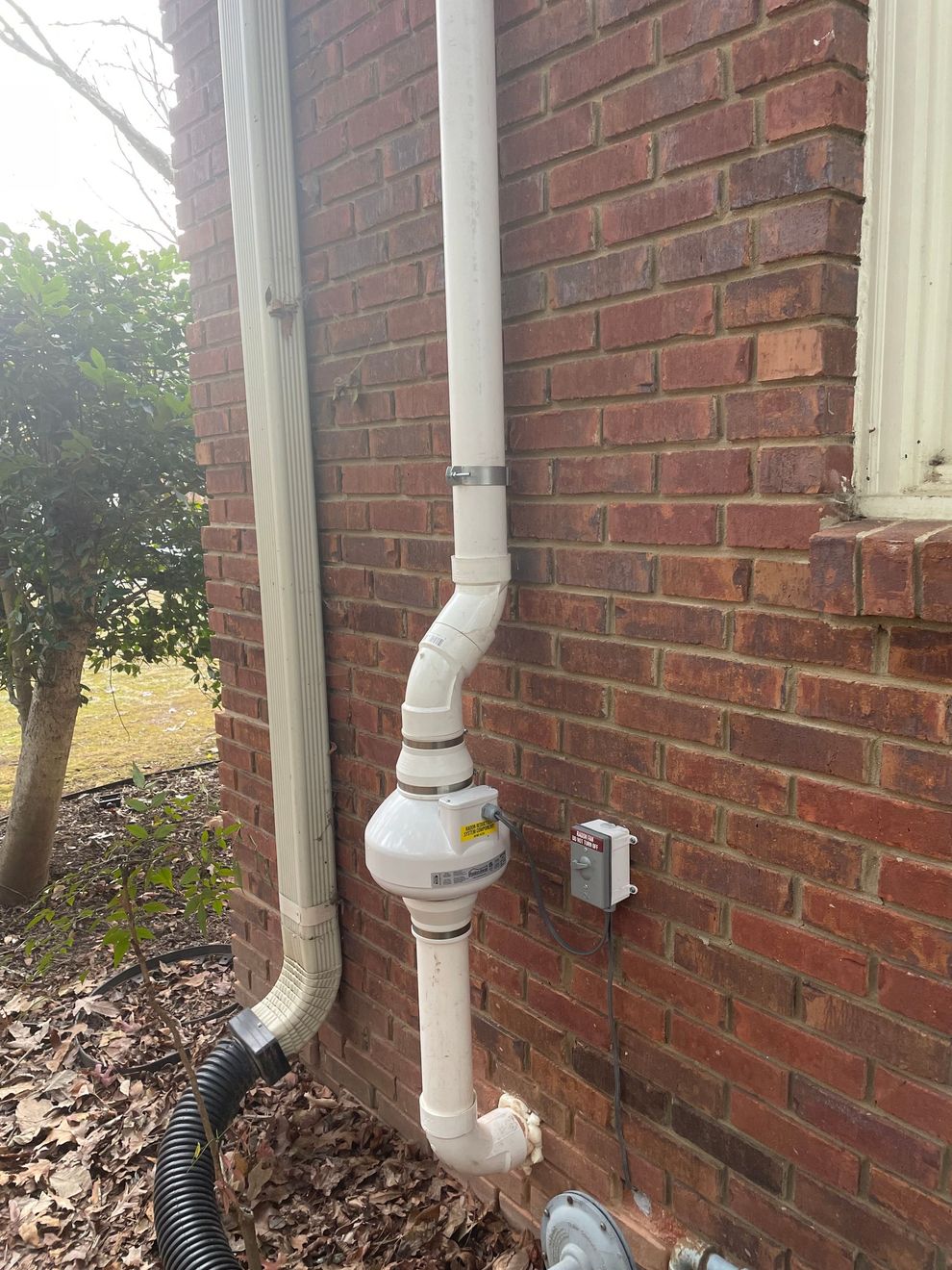 A White Pipe Is Attached to The Side of A Brick Building | Birmingham, AL | Cardinal Construction