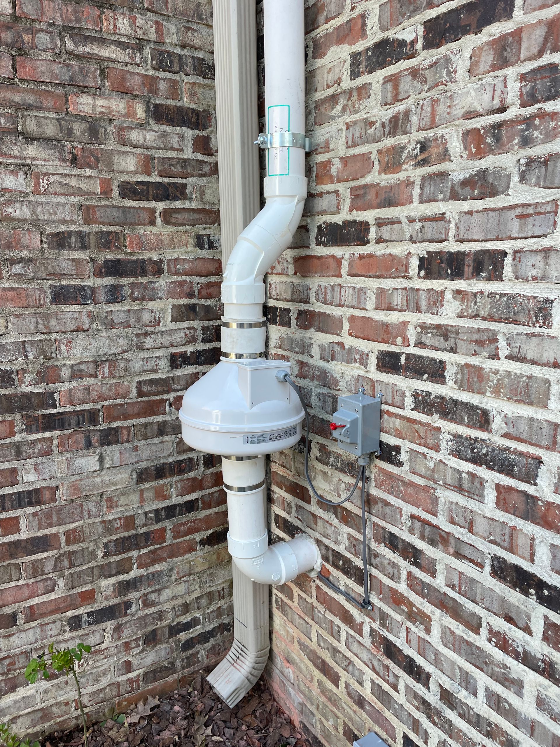 A White Pipe Is Attached to The Side of A Brick Wall | Birmingham, AL | Cardinal Construction