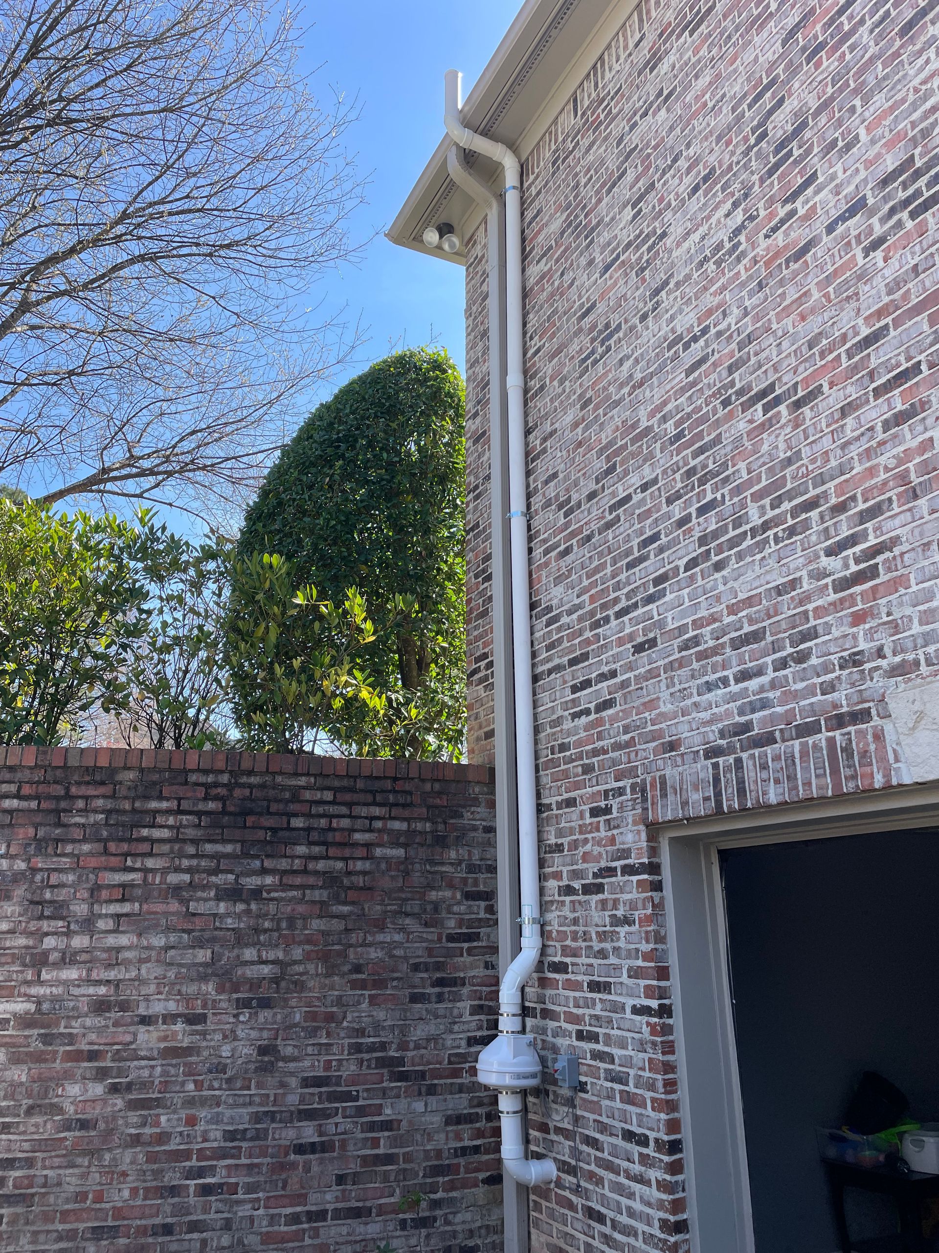 A White Pipe Is Attached to The Side of A Brick Building | Birmingham, AL | Cardinal Construction