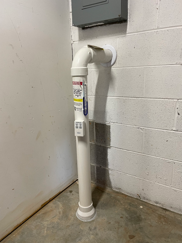 A White Pipe Is Attached to A Brick Wall in A Basement | Birmingham, AL | Cardinal Construction