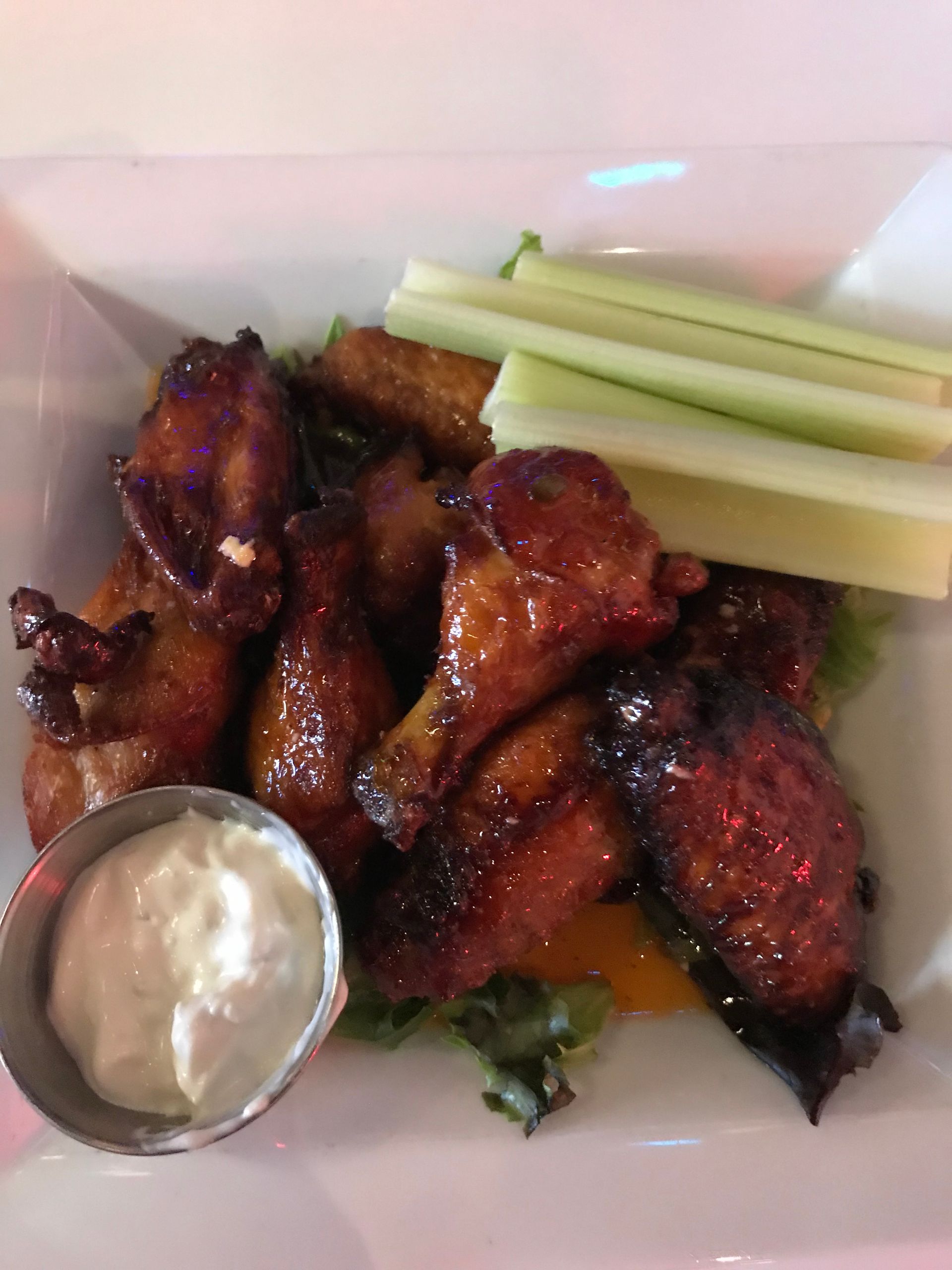 Chicken wings with dipping sauce and celery sticks on a plate.