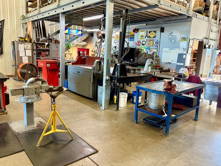 A technician in a hard hat checks equipment while inspecting blue industrial pumps in a mechanical room. A technician in a hard hat checks equipment while inspecting blue industrial pumps in a mechanical room.