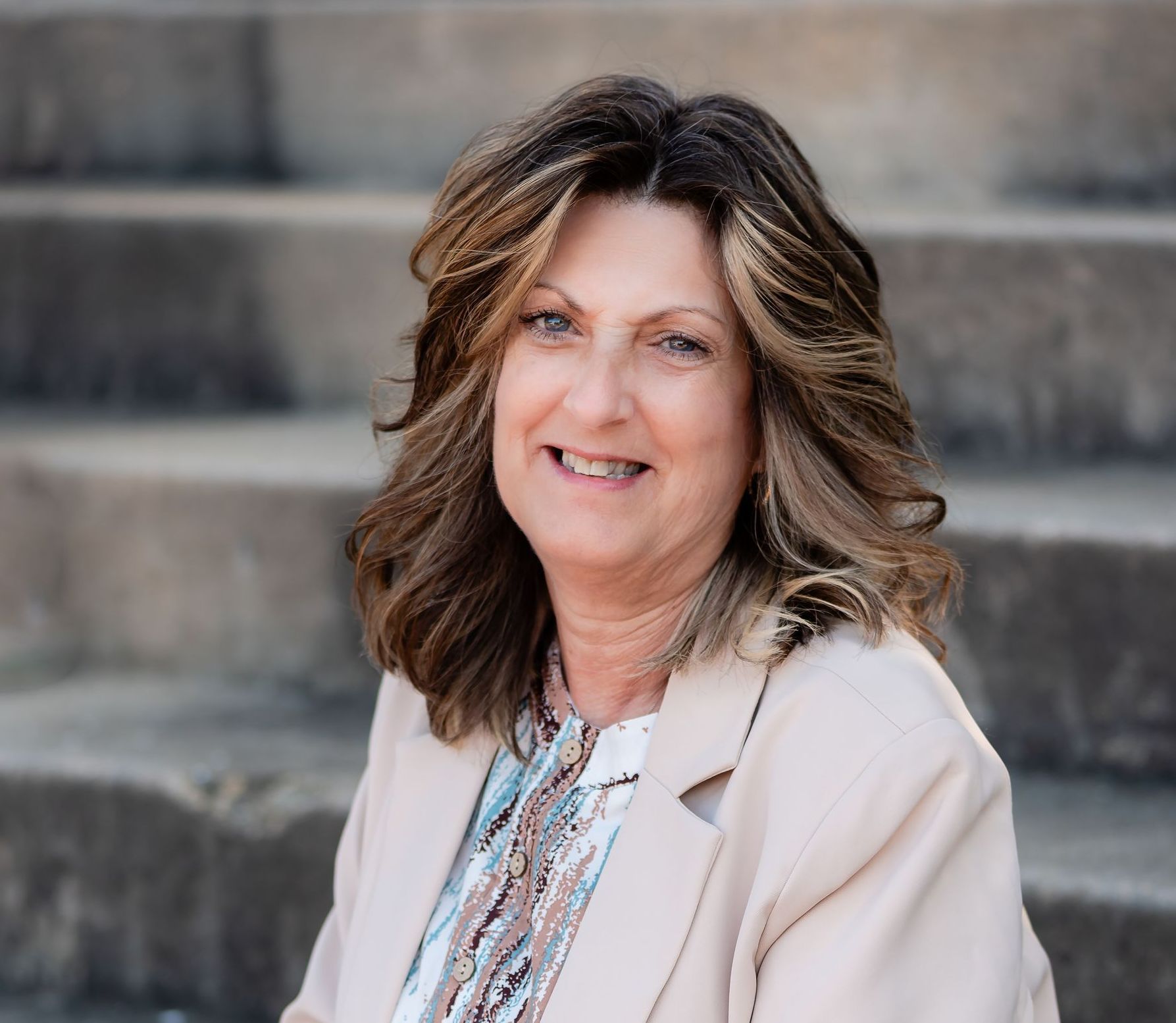 A woman is sitting on a set of stairs smiling for the camera.