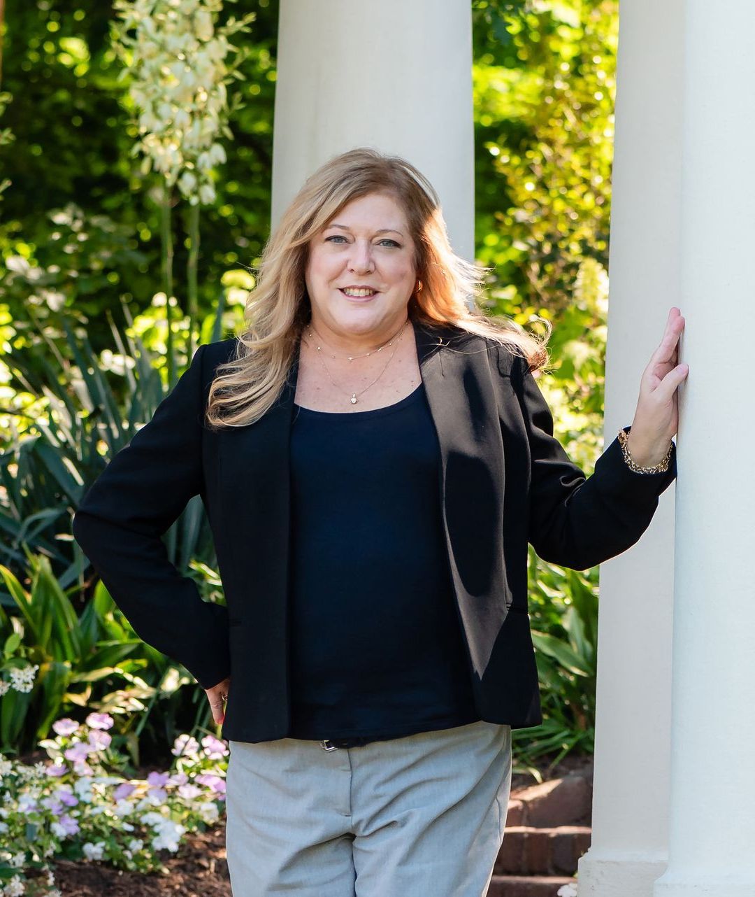 A woman in a black jacket is leaning against a white column