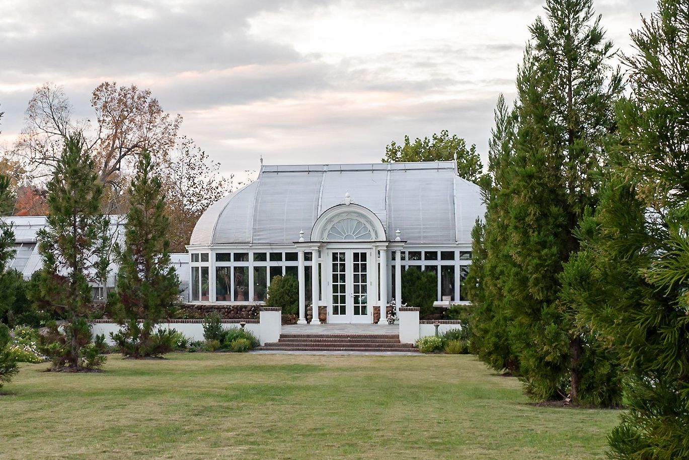 A large white building is surrounded by trees and grass