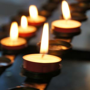 A row of lit candles are lined up on a table