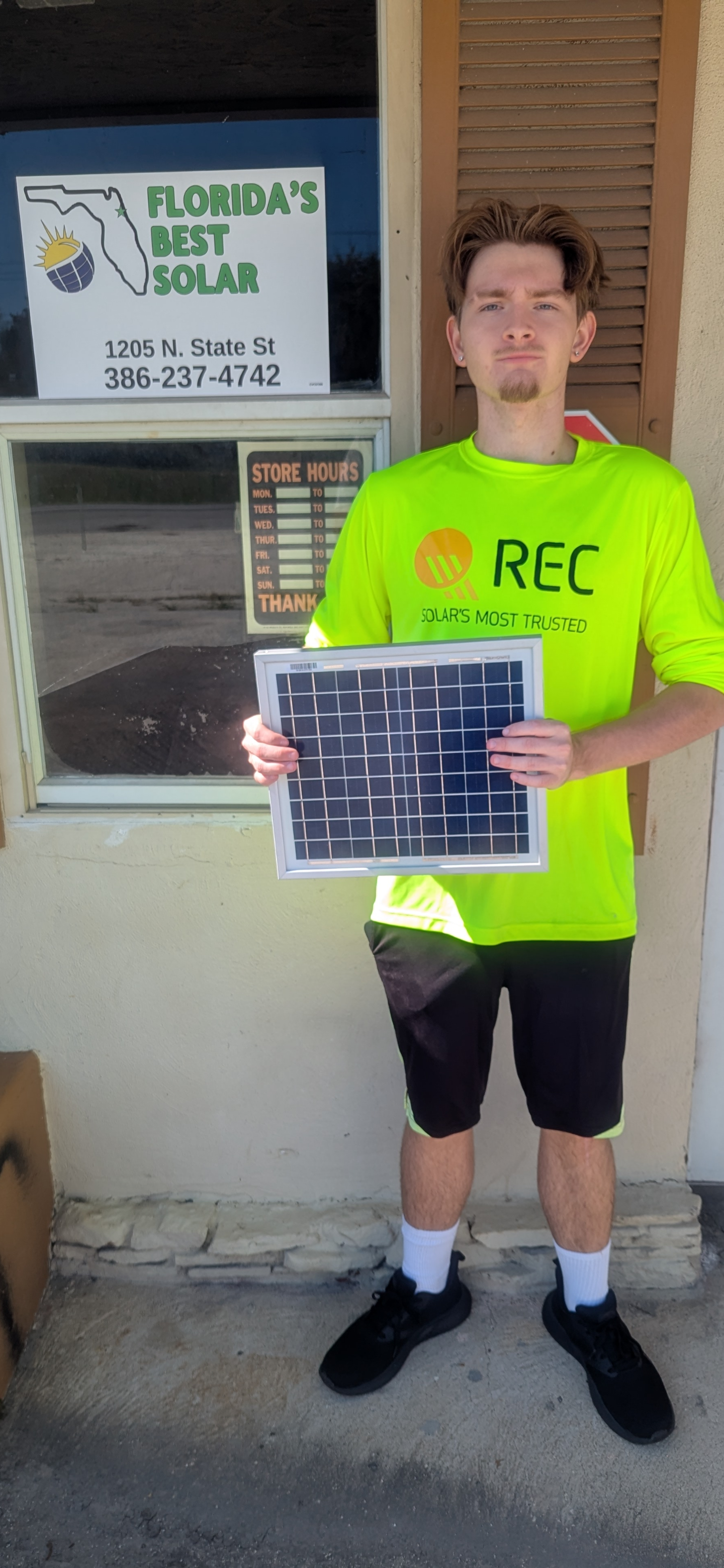Smiling construction worker in hard hat holds solar panel.