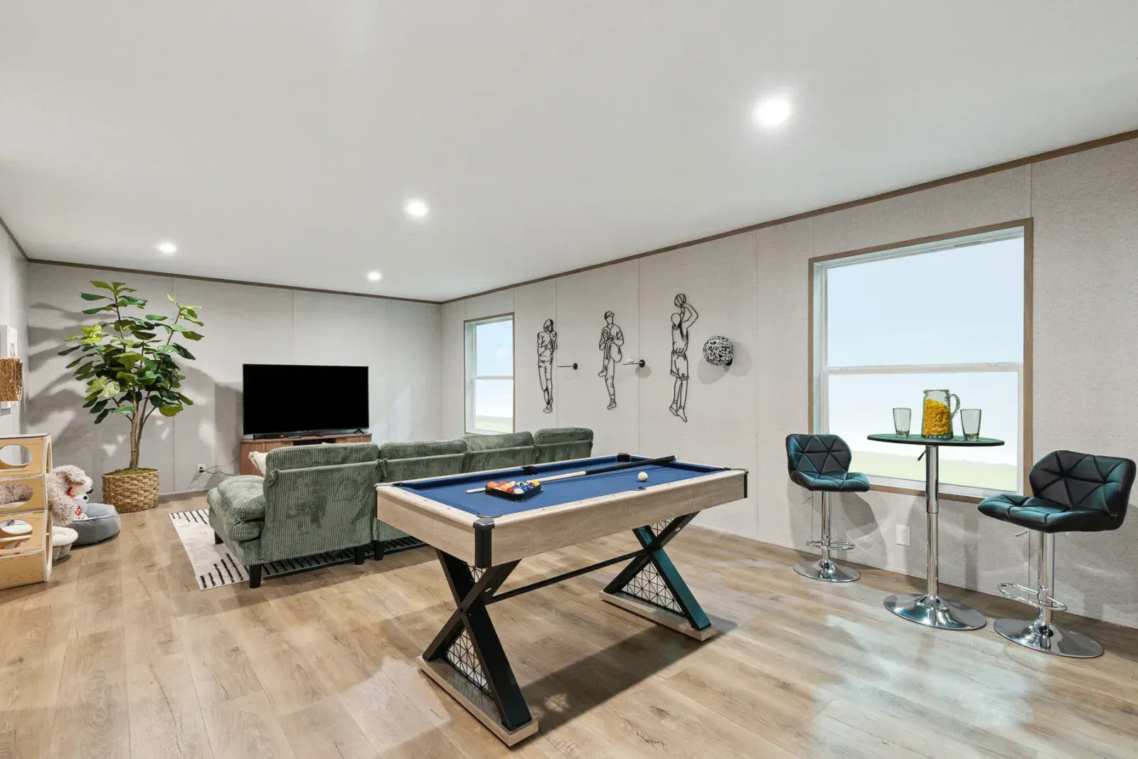Game room with pool table, sofa, bar seating, TV, and decorative wall art.