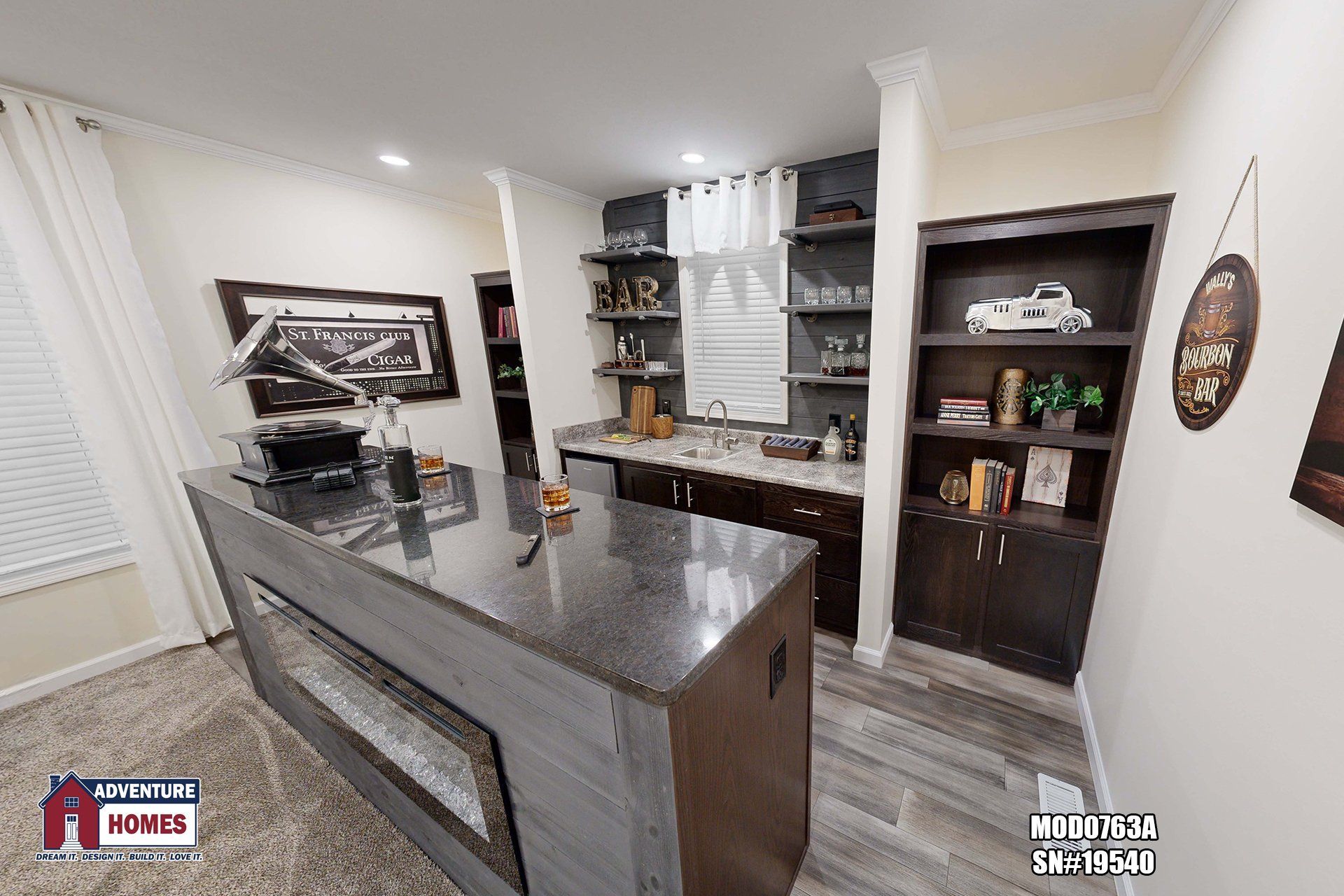 Kitchen with dark gray island, built-in shelving, dark cabinets, and a bar area with open shelving.