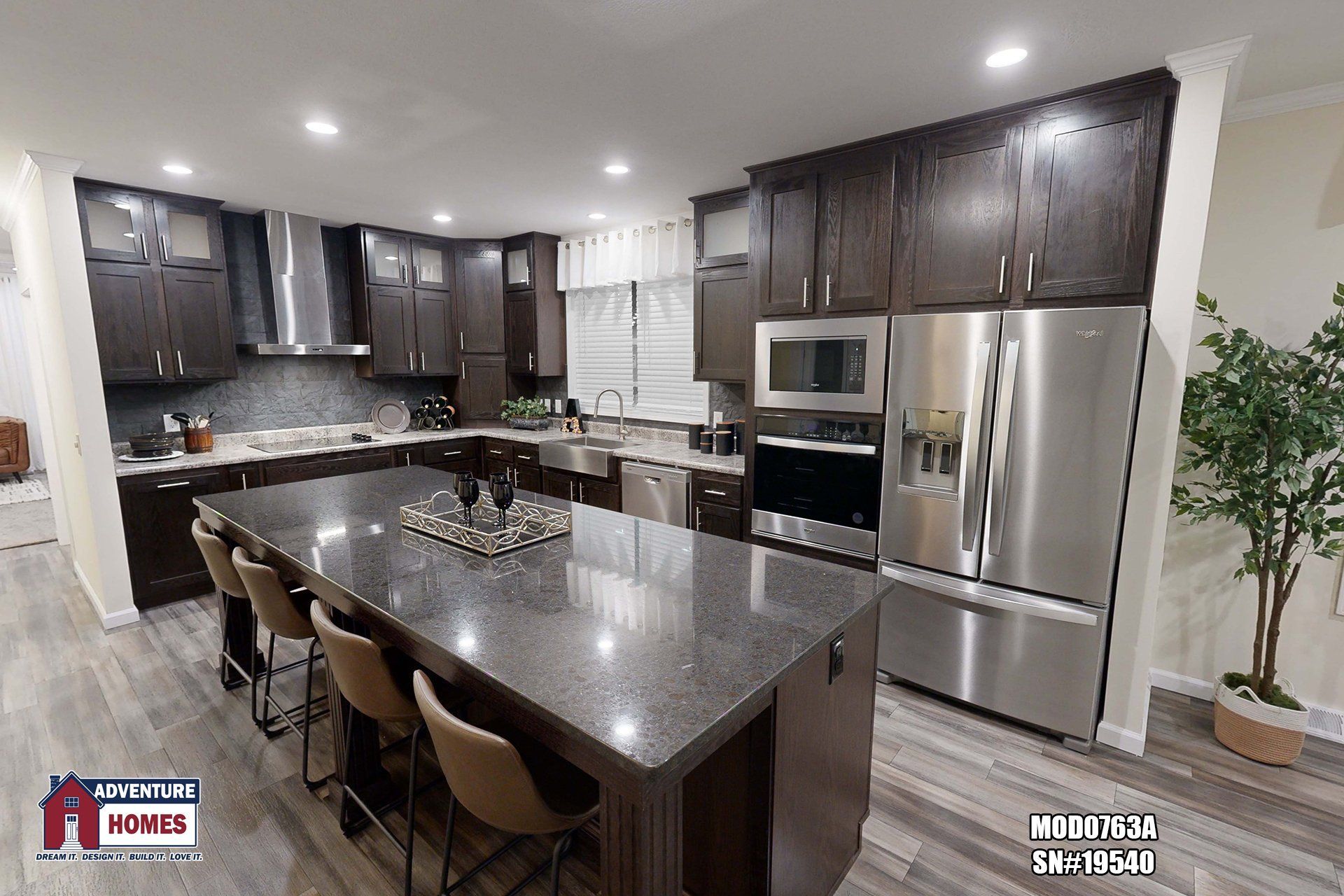 Modern kitchen with dark wood cabinets, stainless steel appliances, and a large island with seating.