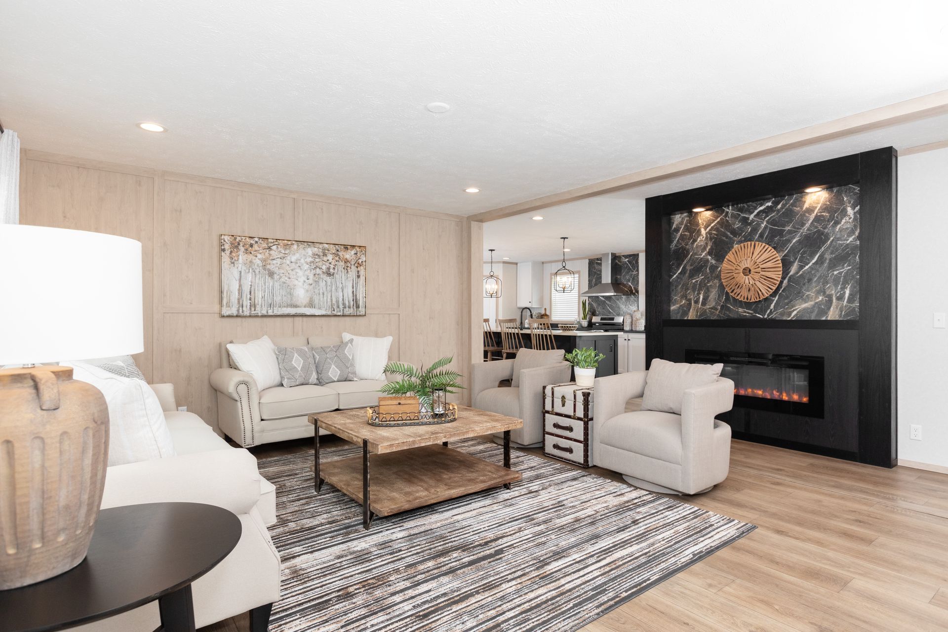 Cozy living room with fireplace, white couches, and open kitchen view.