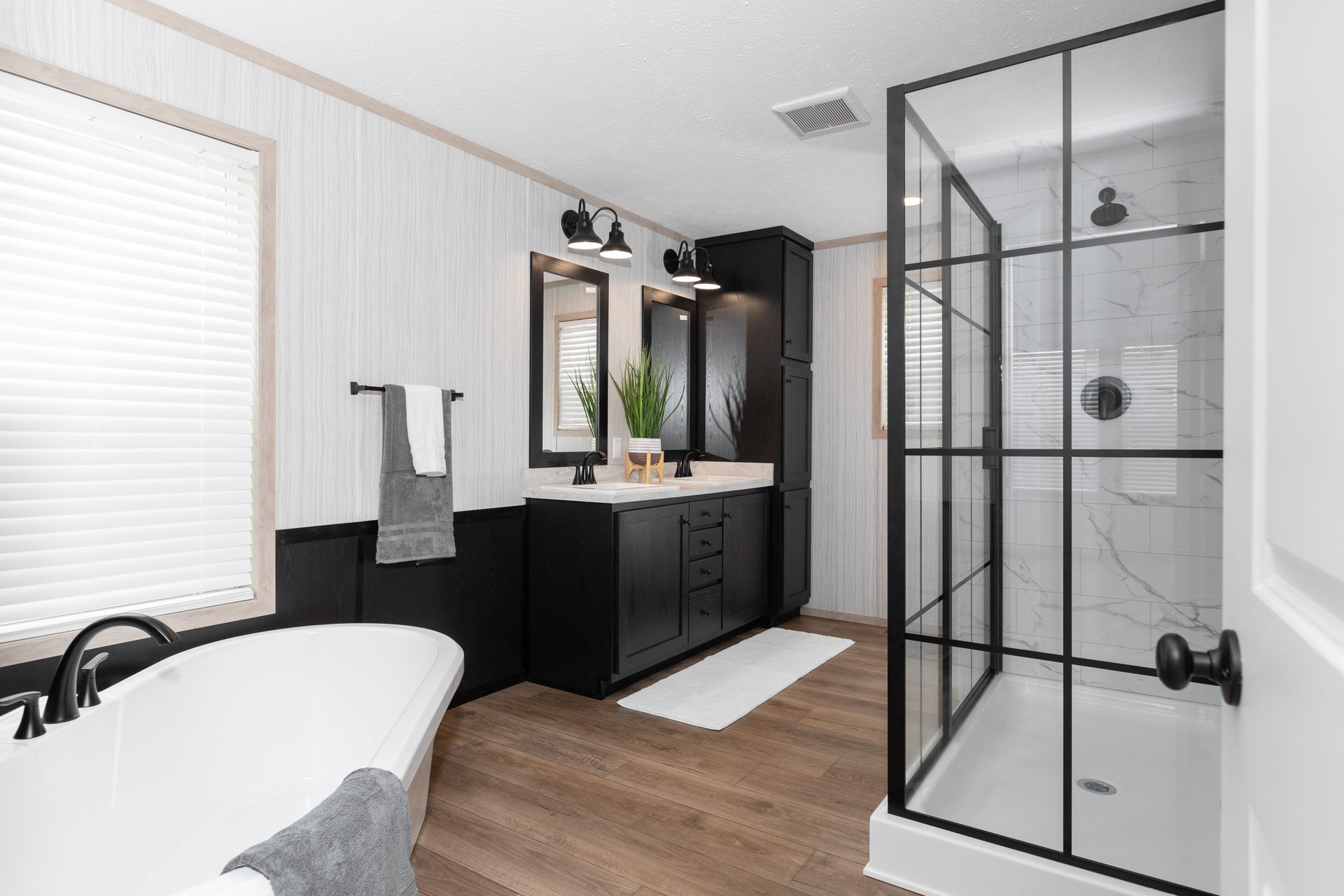 Modern bathroom with black accents: freestanding tub, glass shower, black vanity, and white walls.