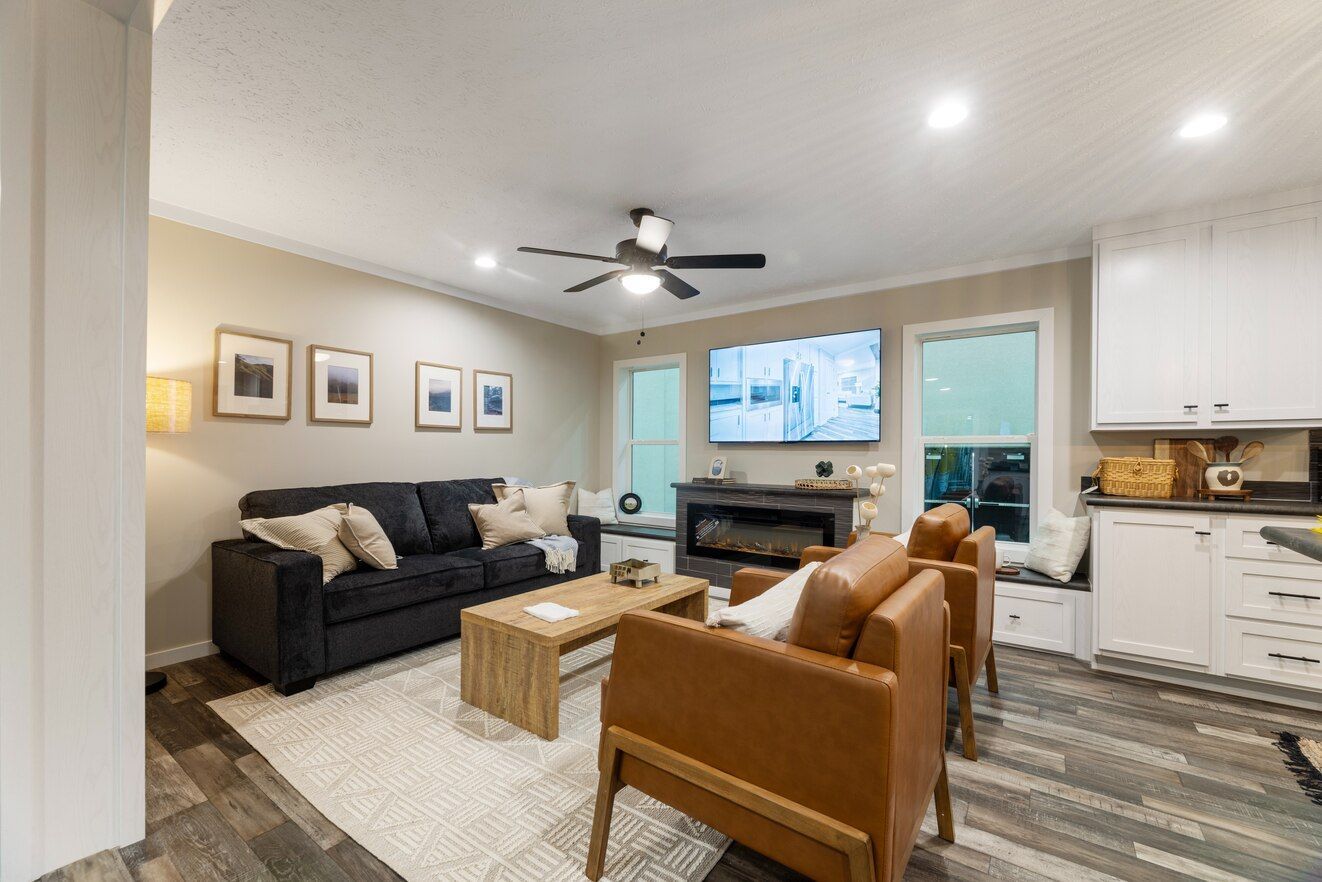 Living room with black sofa, brown chairs, fireplace, and TV.