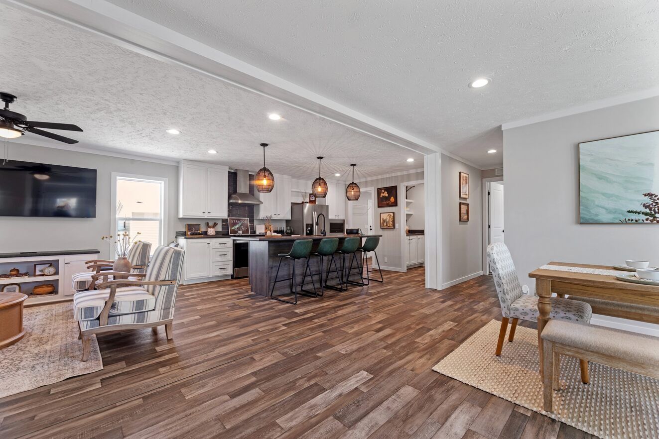 Spacious open-concept kitchen and living area with hardwood floors, dark island, and pendant lighting.