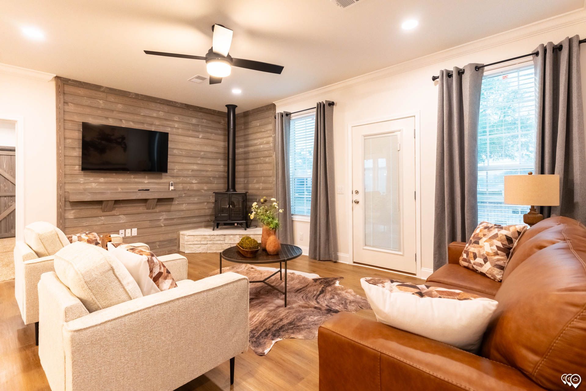 Cozy living room with fireplace, leather sofa, and two armchairs.