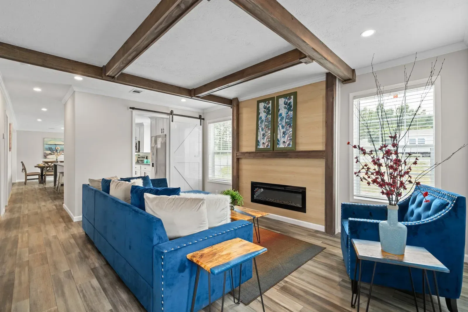 Living room with blue furniture, fireplace, and wood beams.