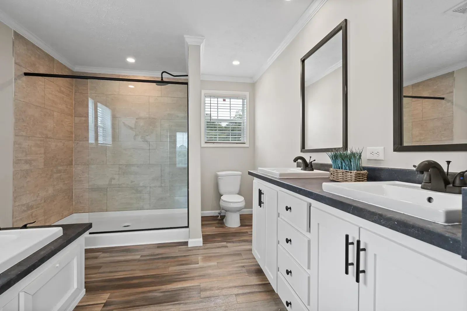 Bathroom with a glass shower, white vanity, and hardwood-style flooring.