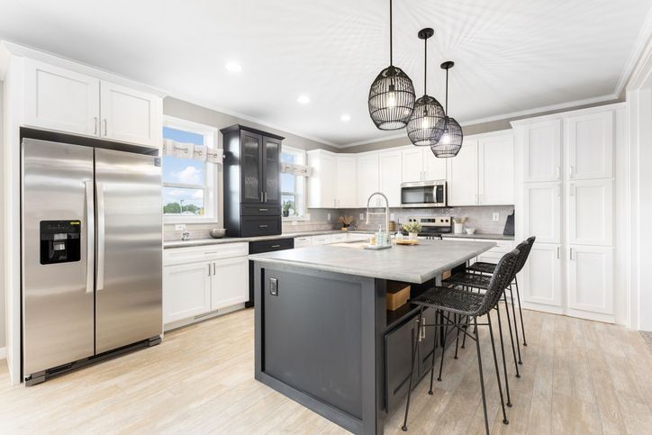Modern kitchen with white cabinets, dark gray island, stainless steel appliances, and pendant lights.