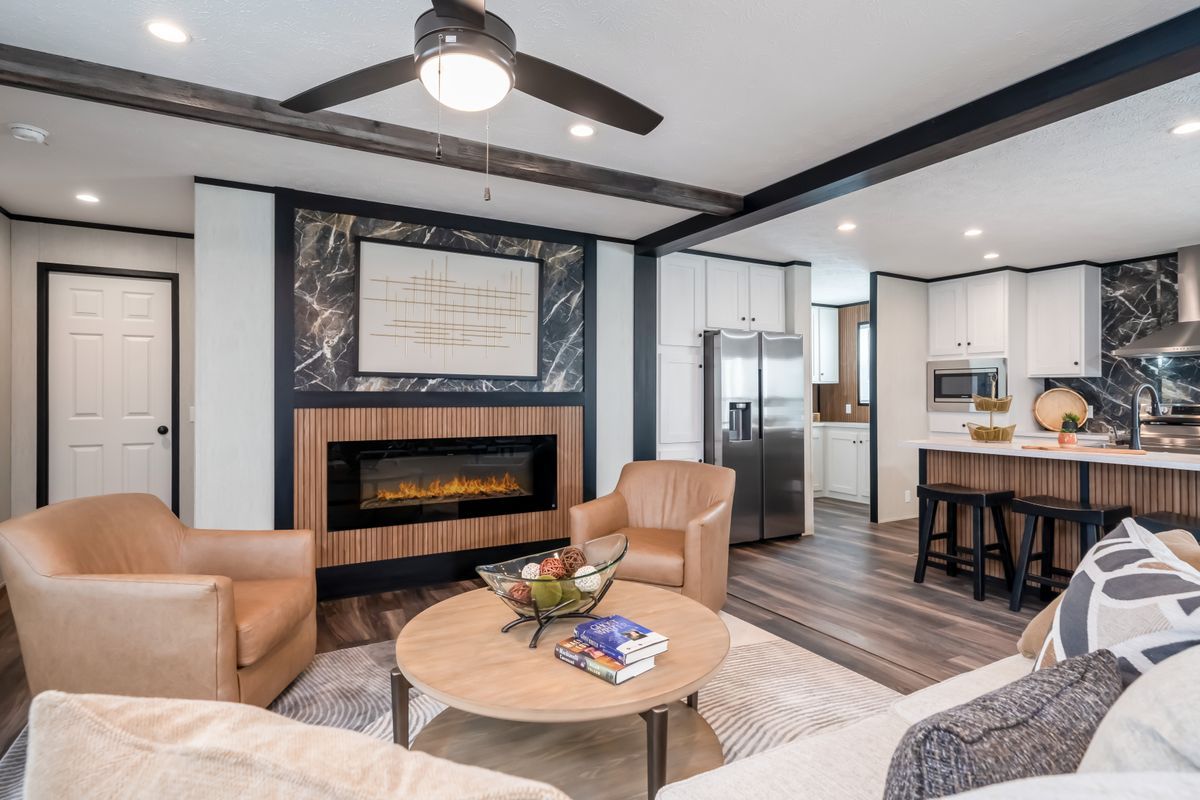 Living room with fireplace, leather chairs, and open kitchen with modern decor.