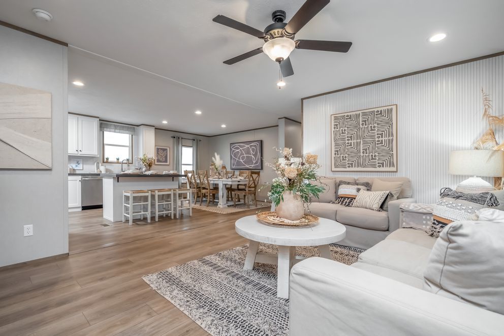 Spacious living room with open kitchen. Beige furniture, wood floors, and neutral walls create a bright, airy space.