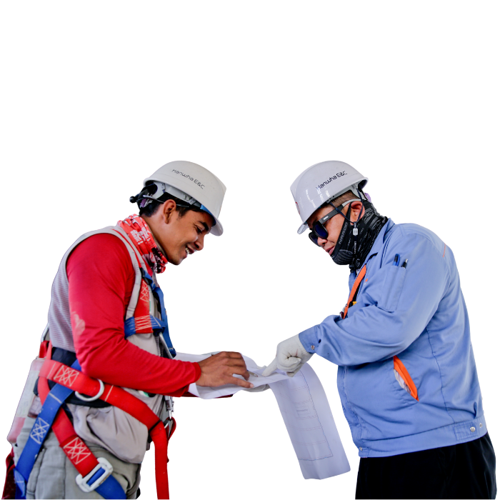 Two construction workers reviewing blueprints, wearing safety gear and hard hats.
