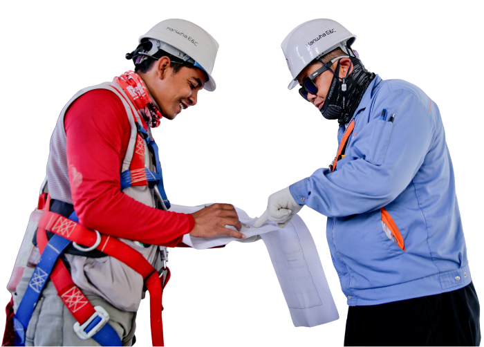 Two construction workers reviewing blueprints, wearing safety gear and hard hats.