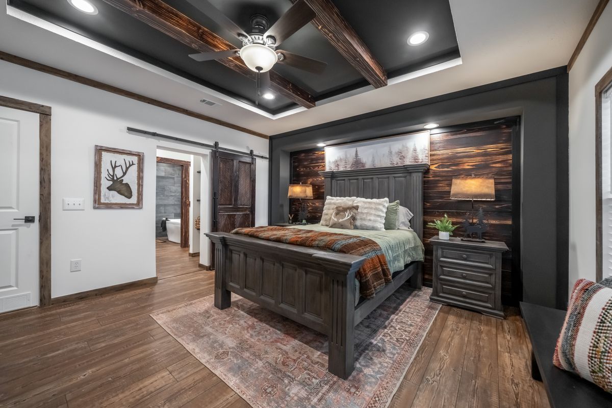 Bedroom with rustic wooden bed, rug, dark ceiling beams, and exposed wood accent wall.