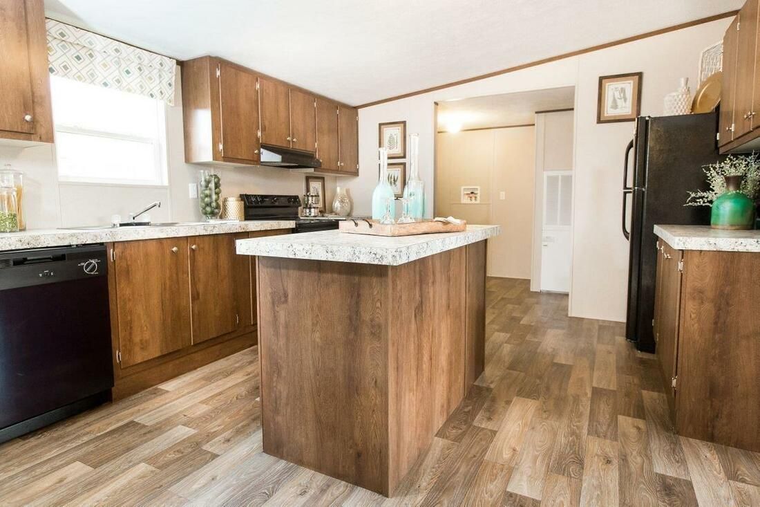 Kitchen with brown cabinets, island, and appliances, with light countertops and flooring.
