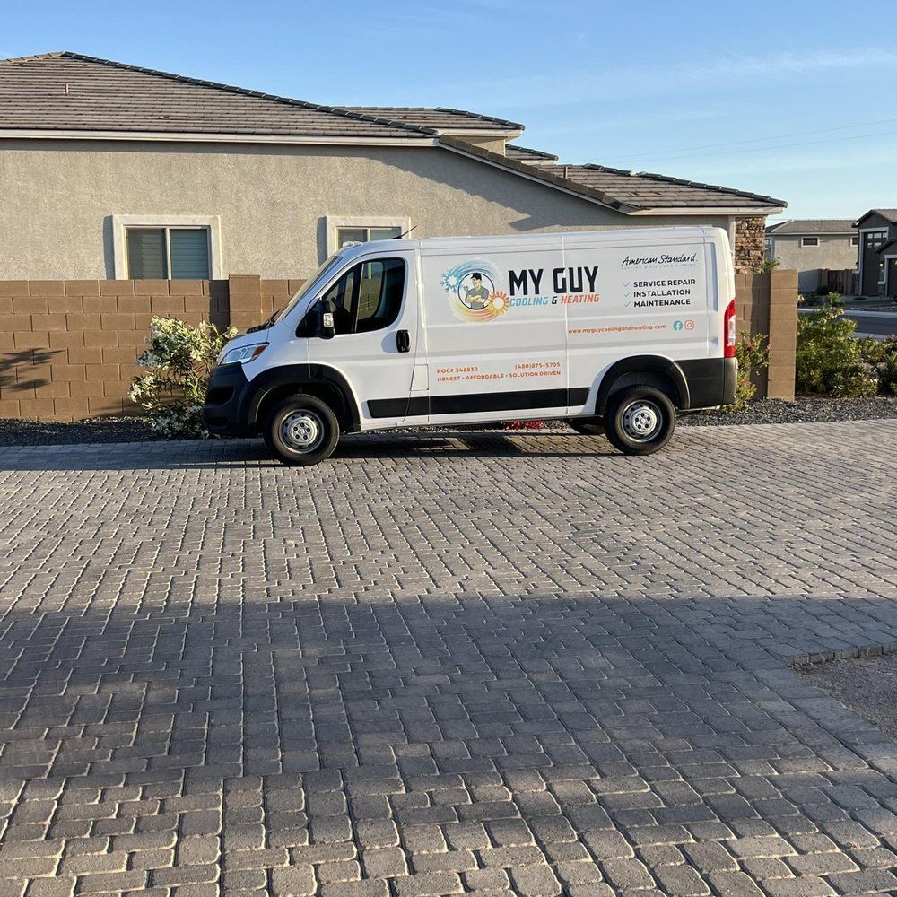 A white van that says my guy is parked in front of a house