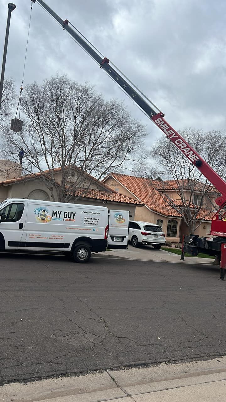 A white van is parked on the side of the road next to a red crane.