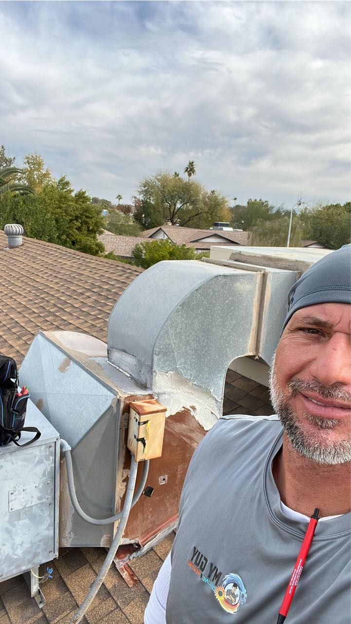 A man is standing on top of a roof with a camera.
