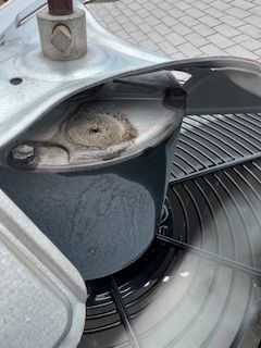 A close up of a fan spinning on a brick sidewalk.