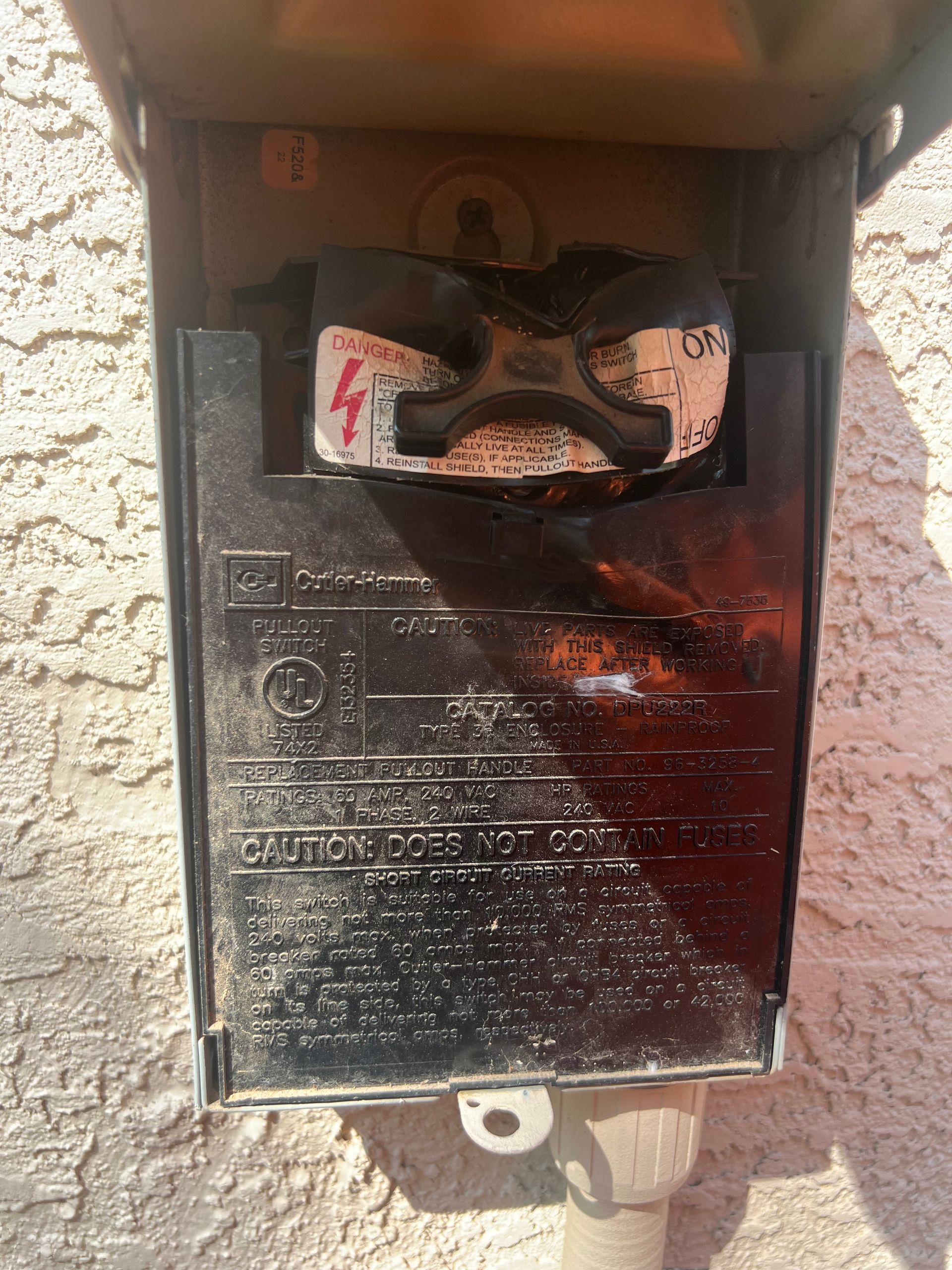 A black electrical box is sitting on a white wall.