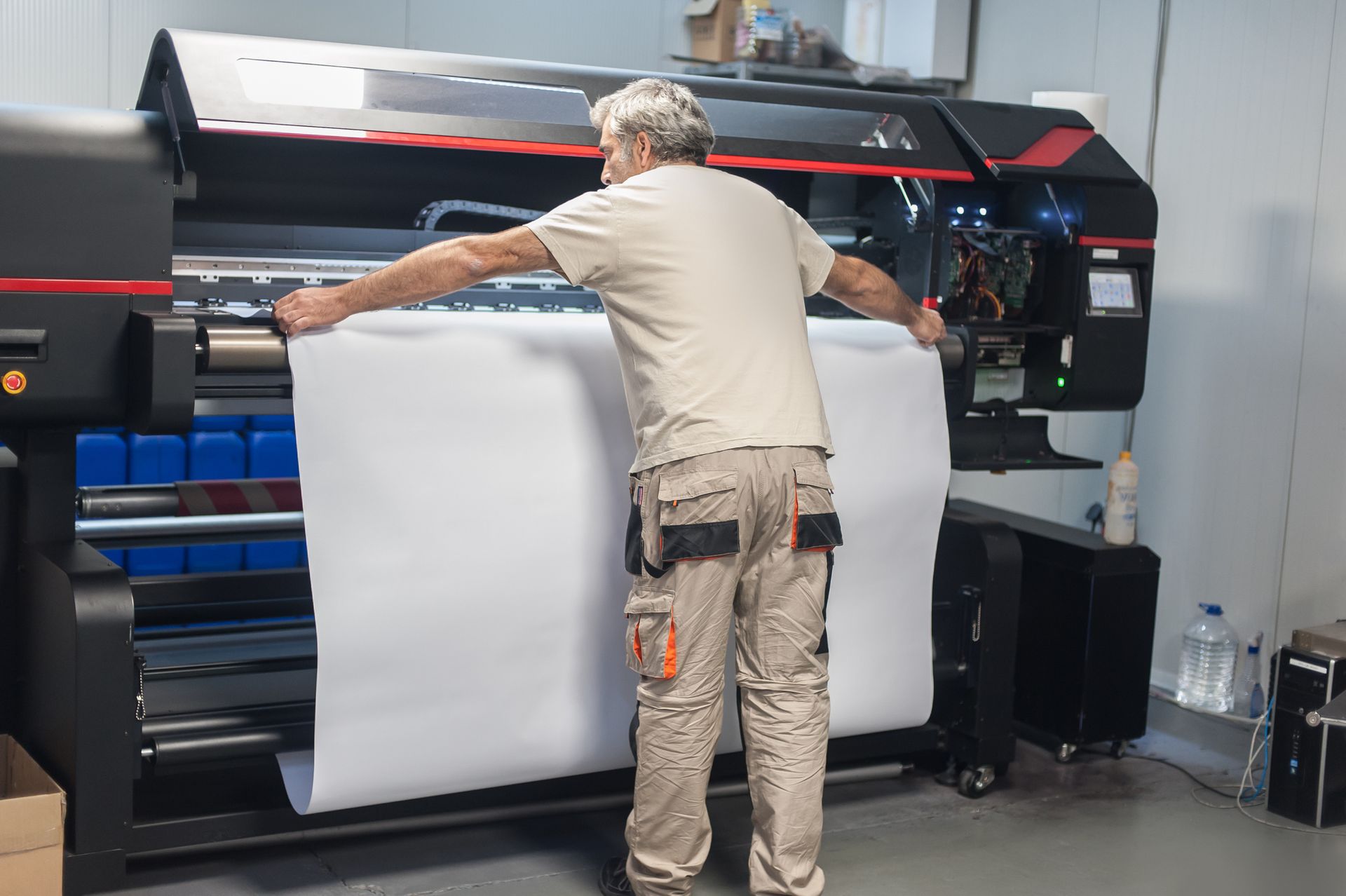 A technician worker operator works on a large premium industrial printer.