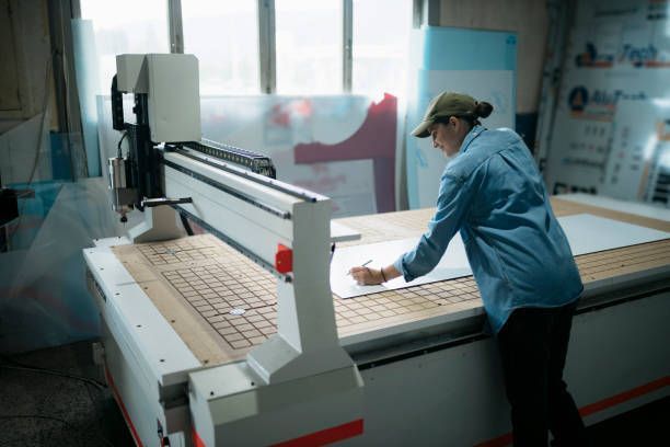 Woman works with sign and plotter, representing the sign manufacturer services in Hampton, VA, by Cardinal Sign Corporation.