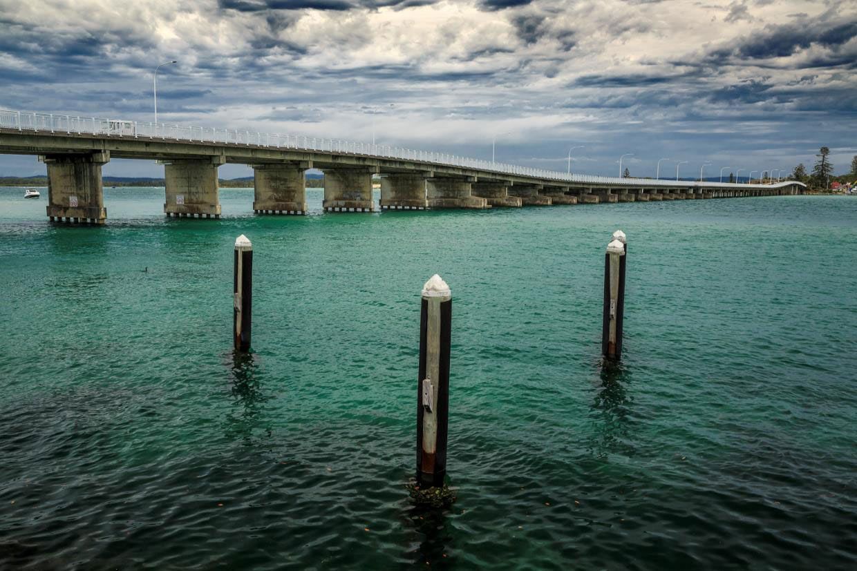 A Bridge Over a Body of Water with A Dock in The Foreground — AAA Equipment Pty Ltd In Forster, NSW