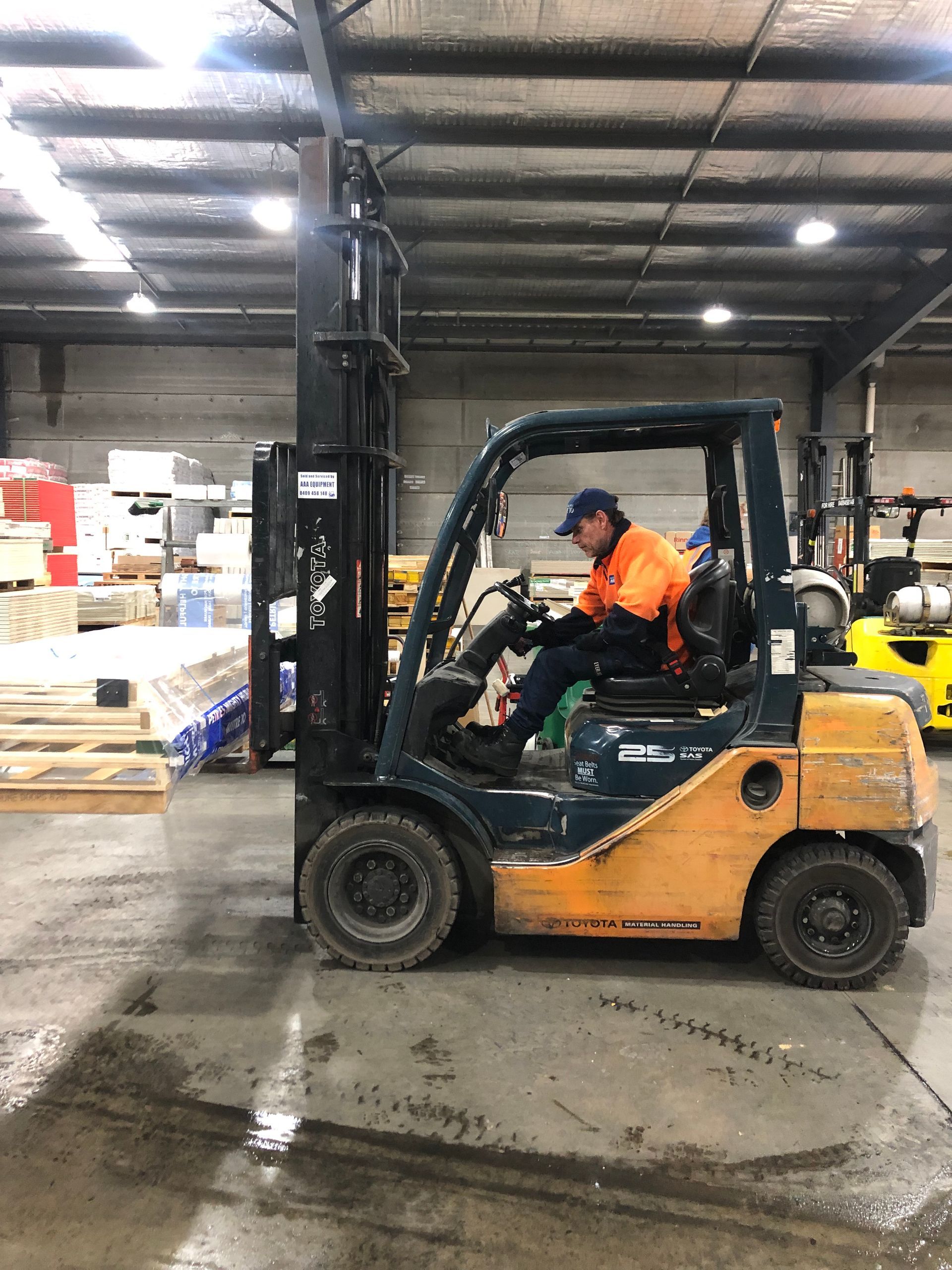 A man driving a  Forklift in a large warehouse— AAA Equipment Pty Ltd In Redbank, NSW