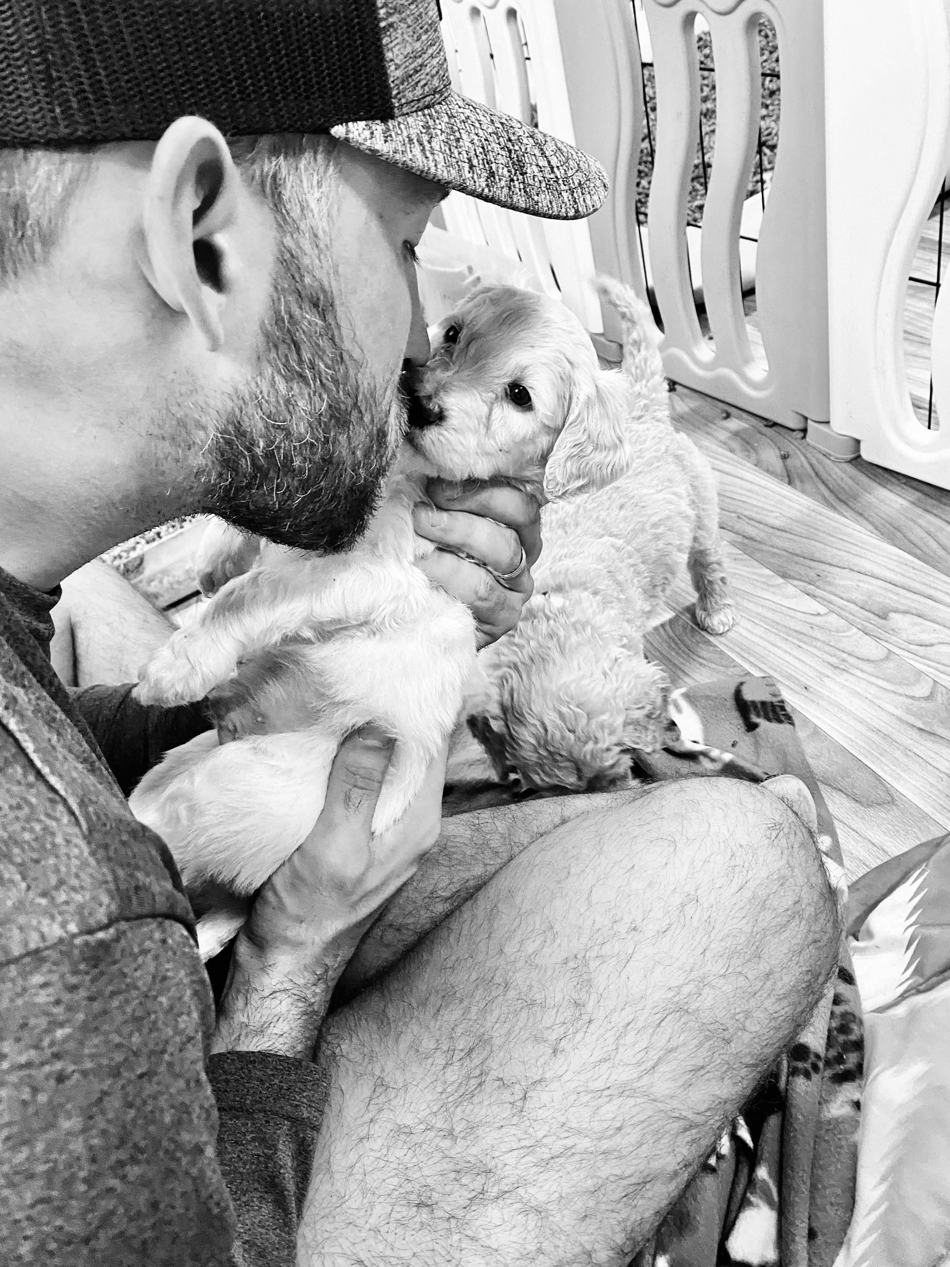 A man is holding a puppy in his lap in a black and white photo.