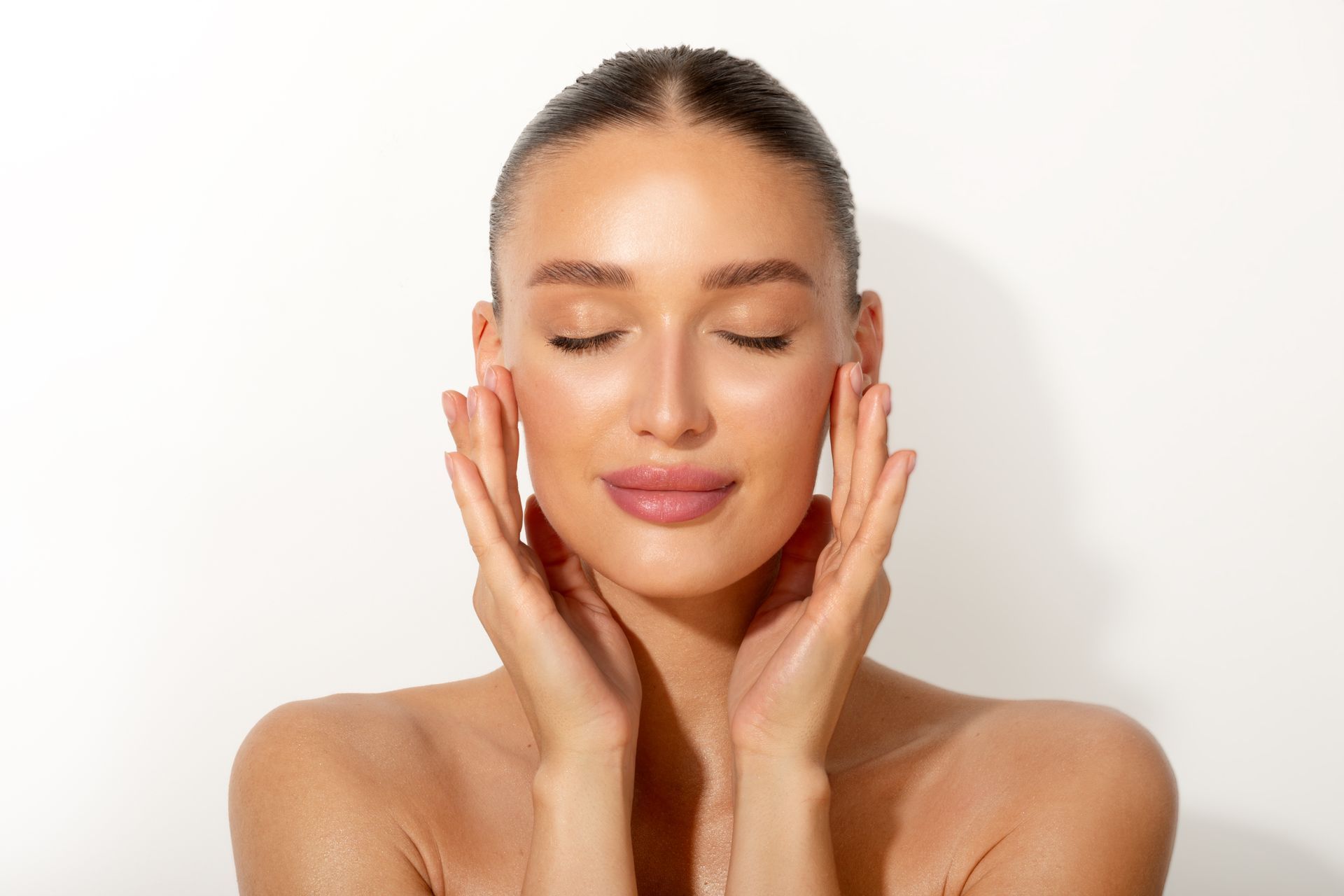 Frau mit geschlossenen Augen, Hände an den Wangen, vor weißem Hintergrund.