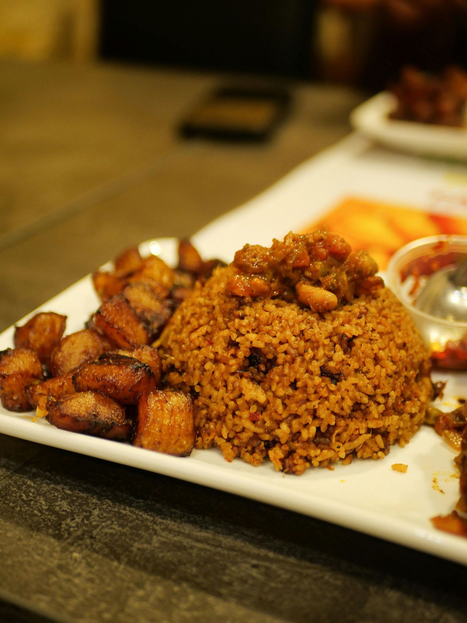 A white plate topped with rice and fried plantains on a table.