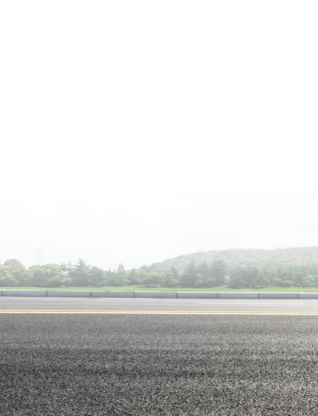 Asphalt road with a blurred green treeline in the distance under a hazy sky | City Side Auto