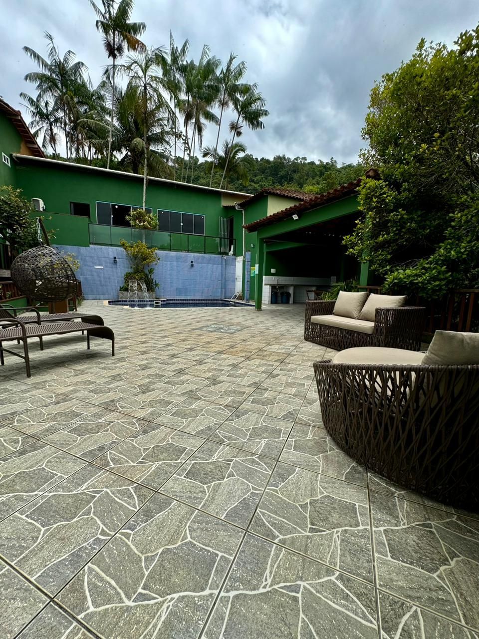 Pátio externo com construção sustentável, piscina e área de estar sob céu nublado.