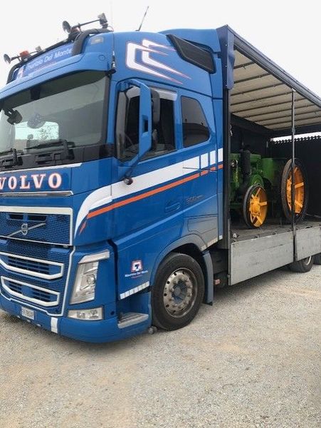 Due escavatori arancioni su un camion a pianale accanto a una cabina gialla in autostrada
