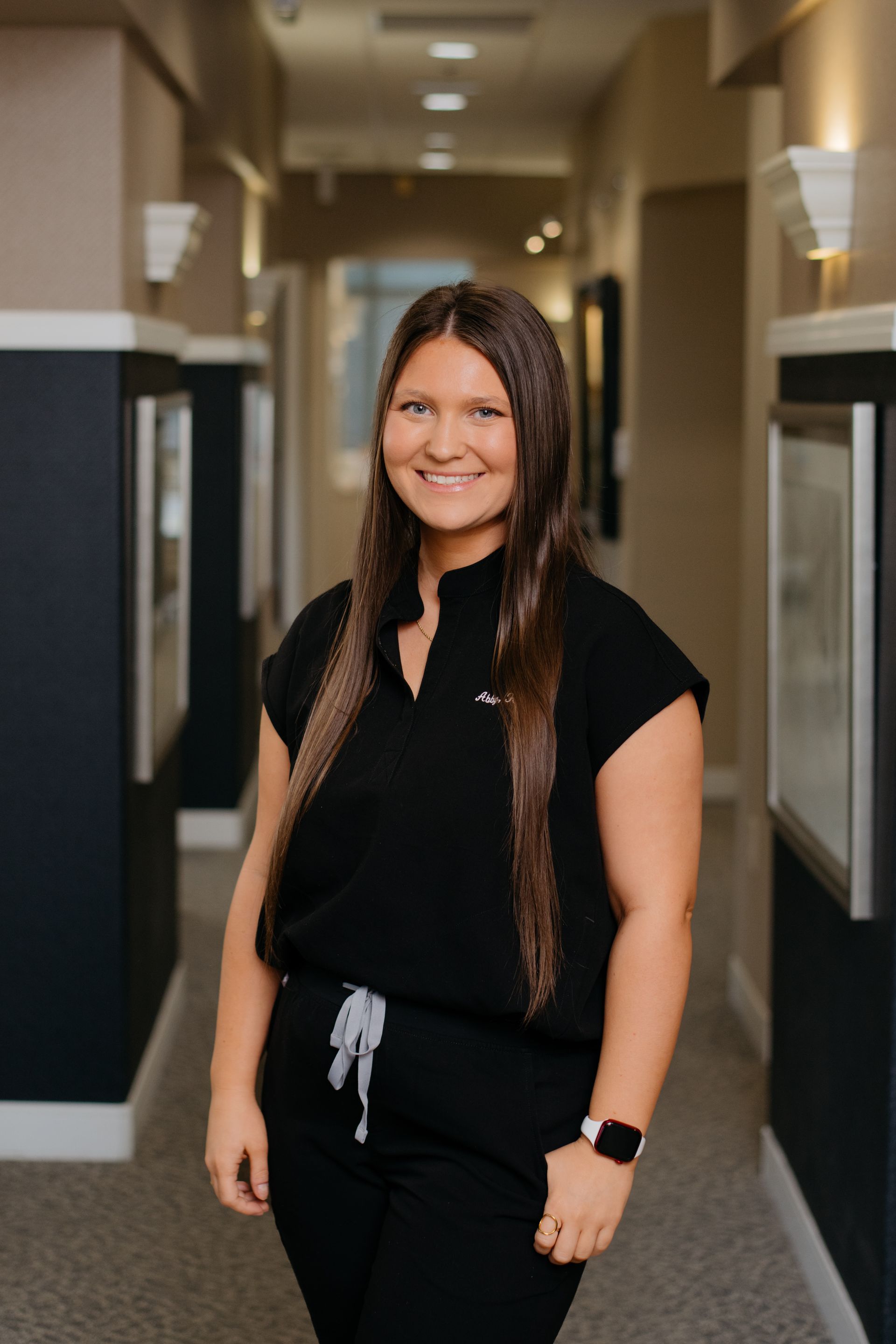A woman in a black shirt and pants is standing in a hallway.