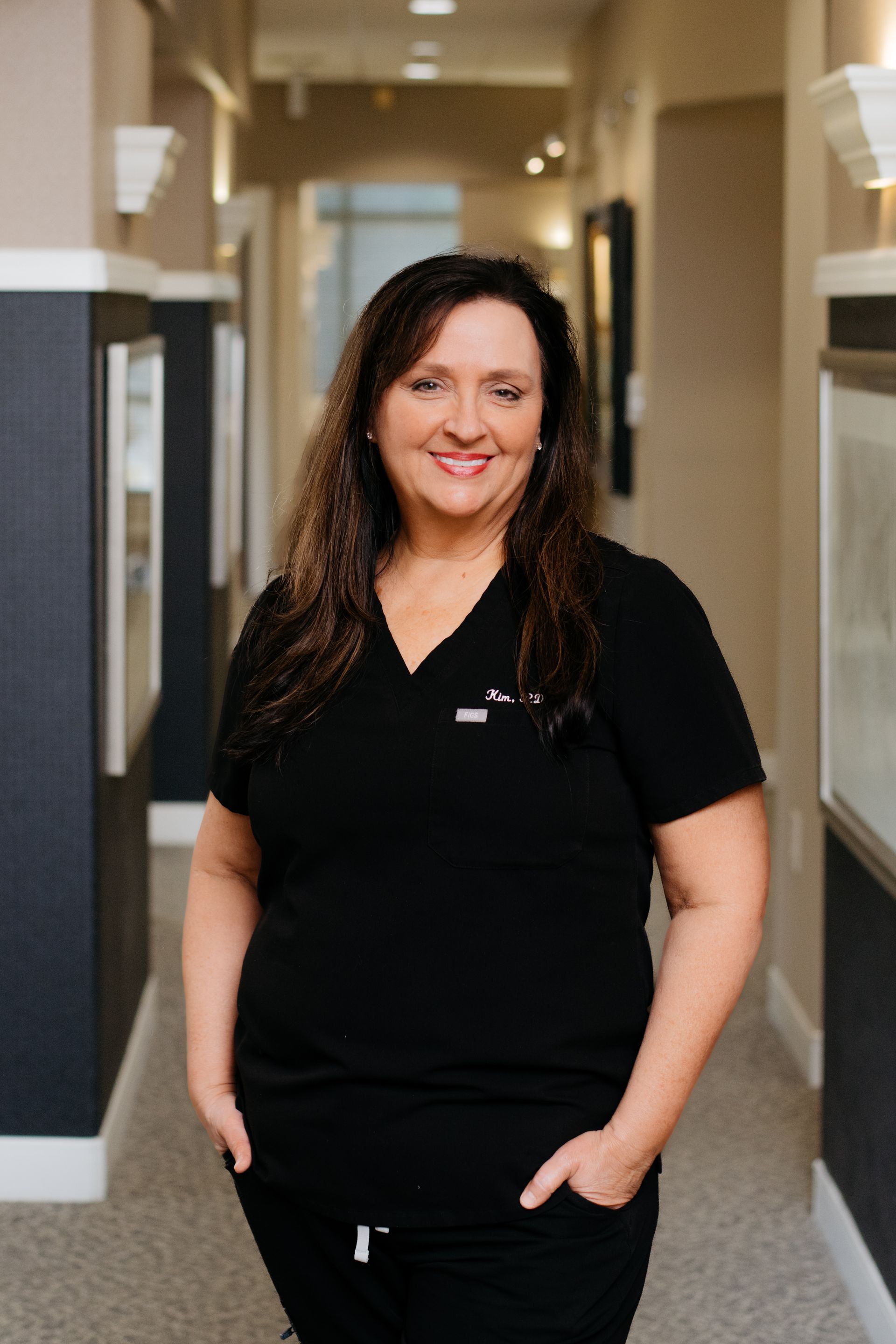 A woman is standing in a hallway with her hands in her pockets.